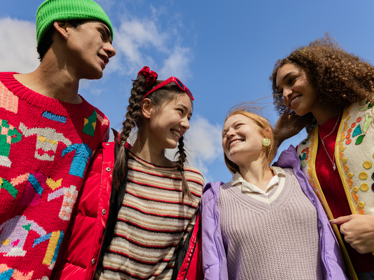 Teens in a group with a blue sky in the background.