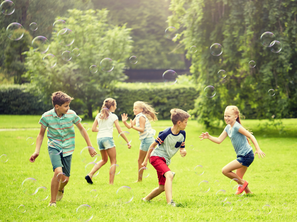Kids playing with bubbles in a green garden space.