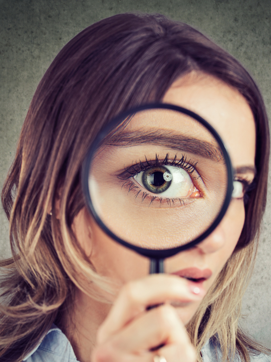 young woman with magnifying glass to her eye