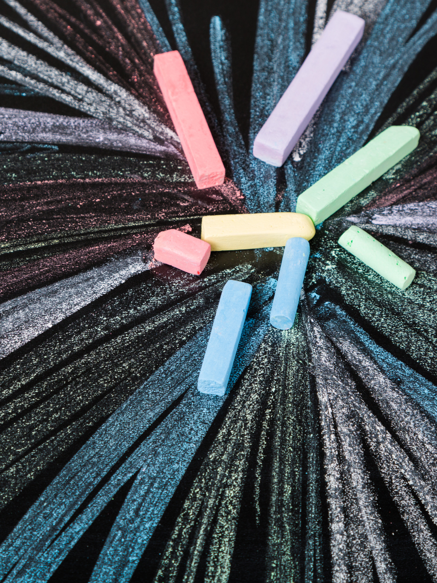 Colorful pieces of sidewalk chalk form a firework shape.