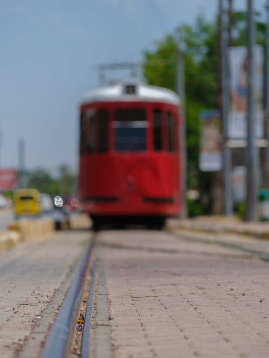 A quaint red trolley car is just out of focus, set against a clear blue sky.