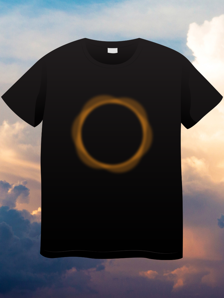 A black t-shirt with an orange circle resembling a solar eclipse on the front of it with a blue sky in the background. 