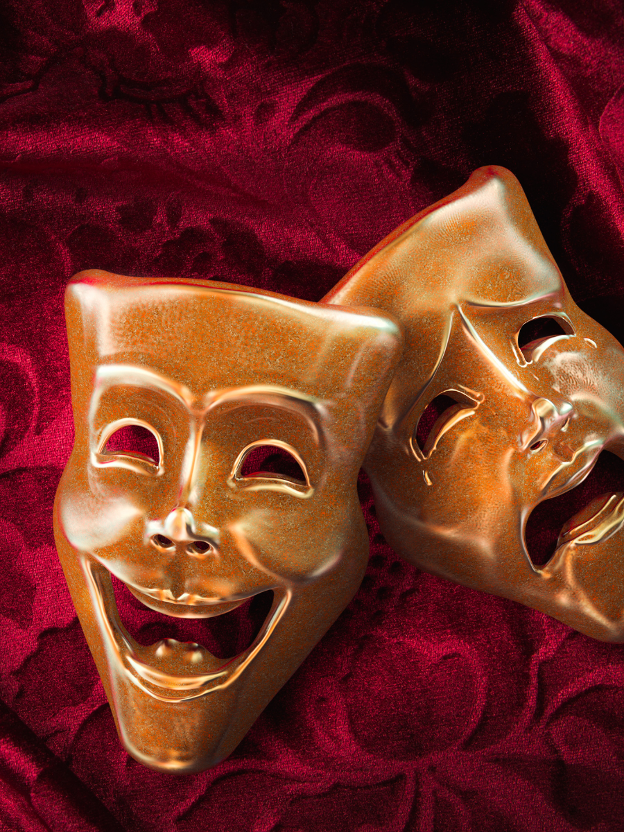 gold comedy and drama masks laying on maroon damask fabric