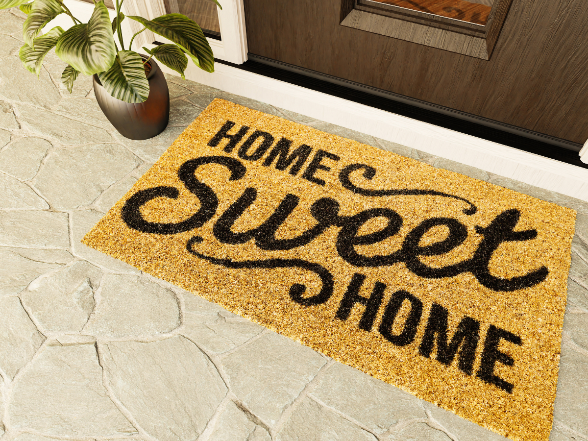 Doormat reading Home Sweet Home in front of a brown door