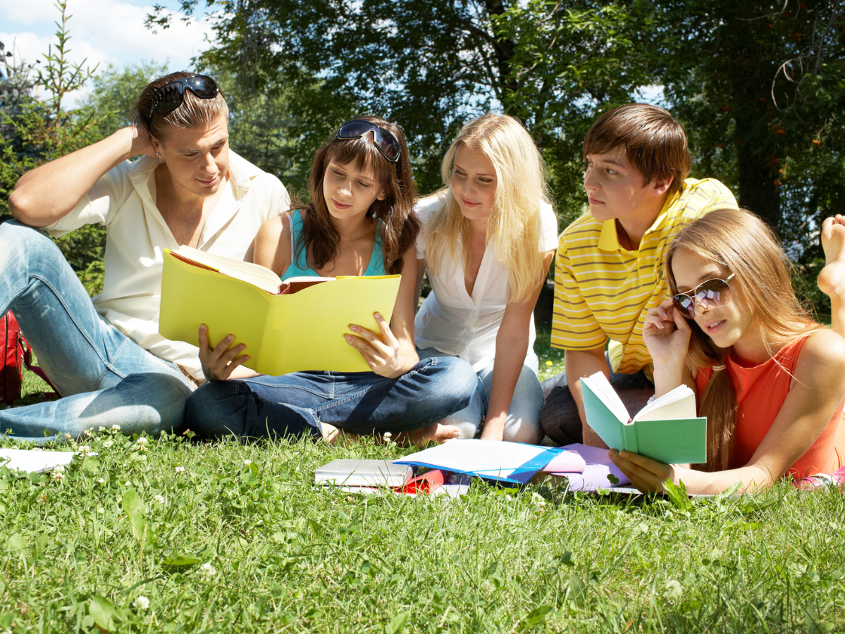 Teens reading on the grass.