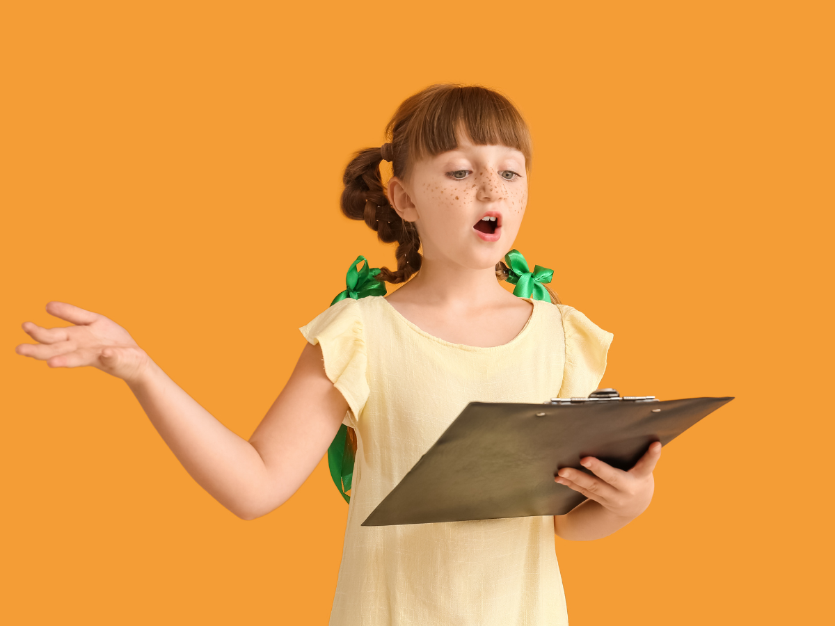 Child reading from a script in front of an orange background.
