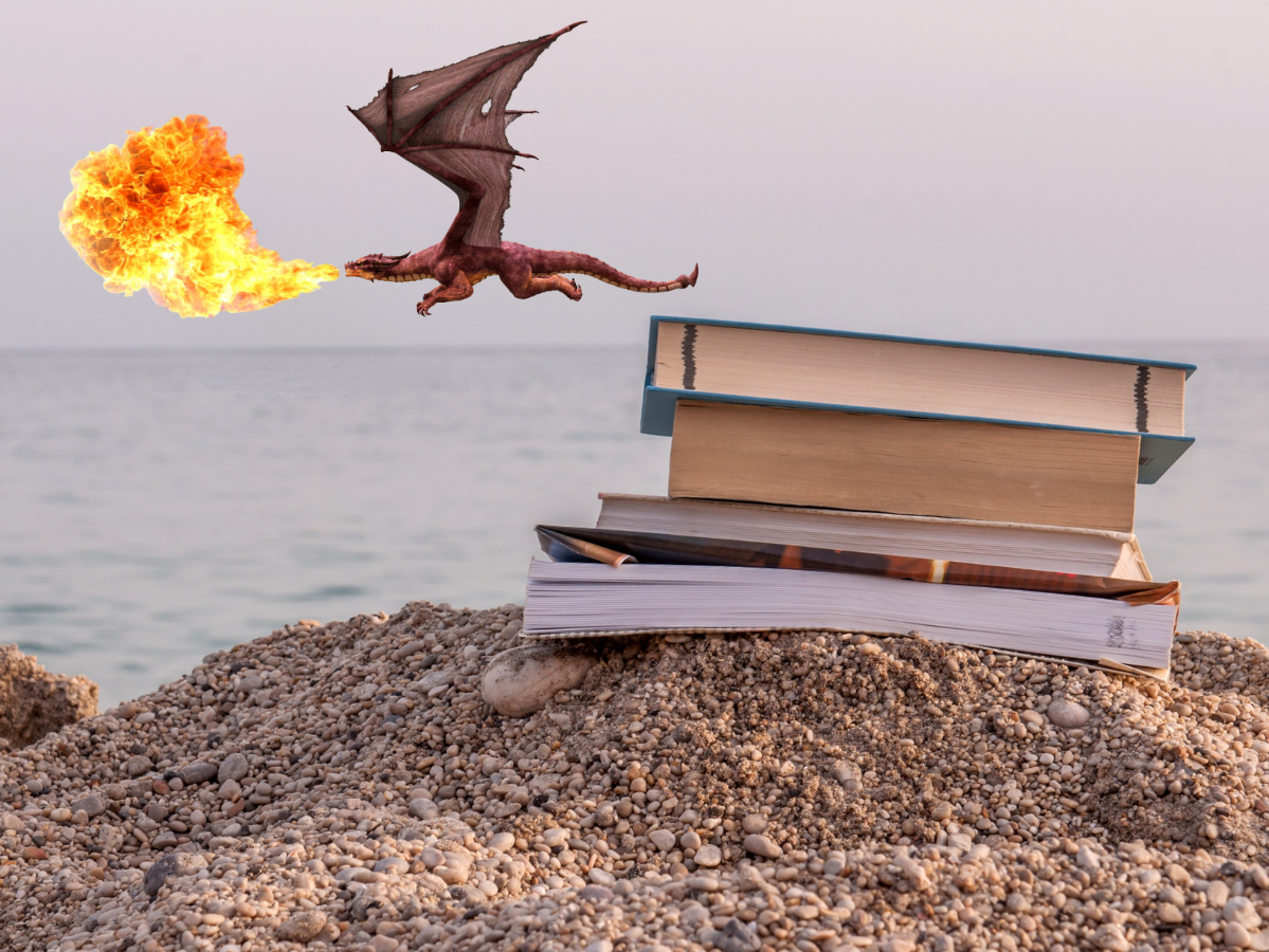 A pile of books on a beach with a fire-breathing dragon flying in the background.