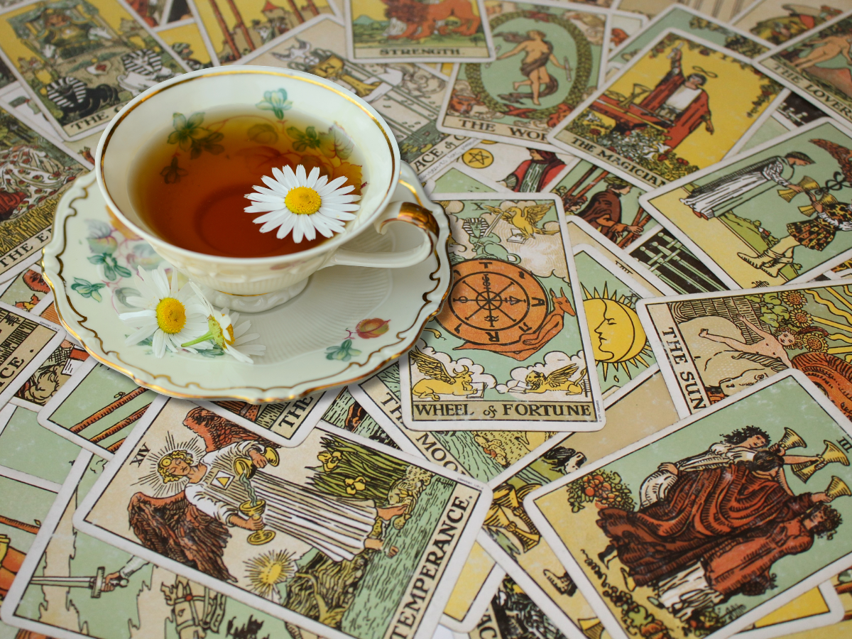 A steaming cup of tea beside an open tarot deck