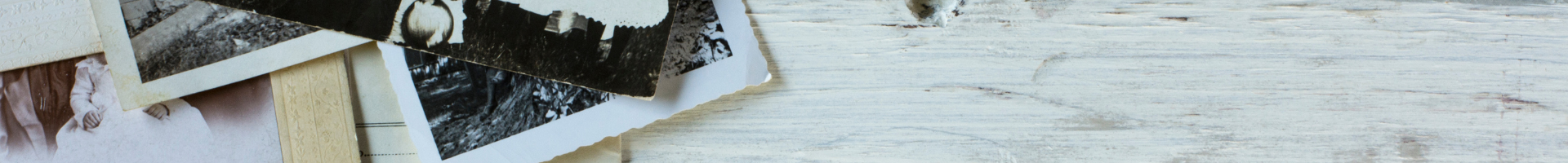 Edges of a group of vintage photos on a white wooden table top