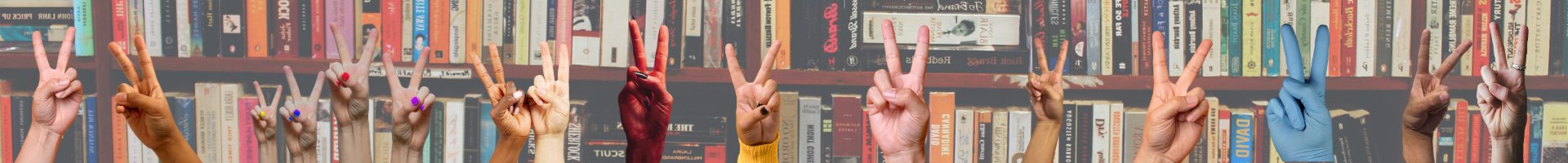 Several hands holding up the two-finger peace symbol in front of bookshelves.