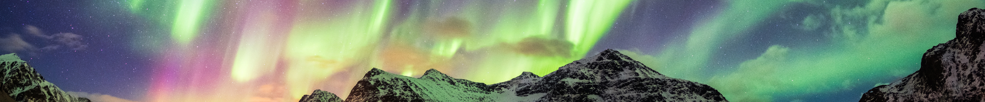 green and purple northern lights over a mountain range