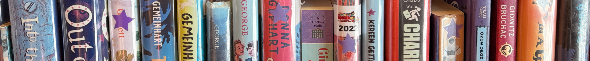 The spines of several books on the shelf, some of which have purple star stickers at the top.